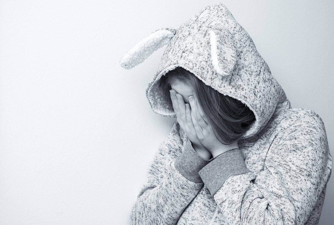 A girl hiding her face with her hands